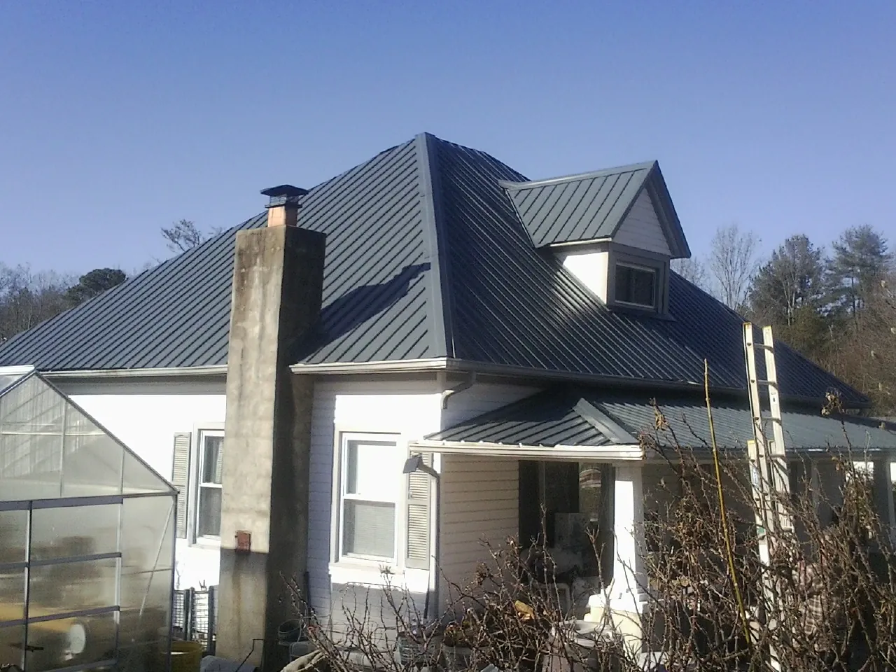 Dark blue standing seam metal roof on a white farmhouse with dormer — Slate & Tile Roof Repair by Roofing Brothers in Milmay