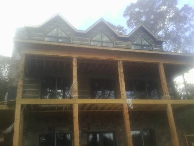Dormers and porch framing on a large log home under construction — Roof Coating work by our crew in Milmay