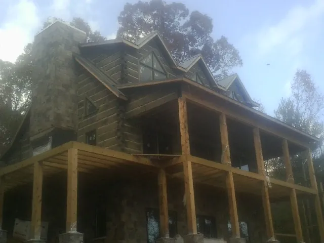 Stone chimney and dormers on a large log home with a timber porch in Milmay