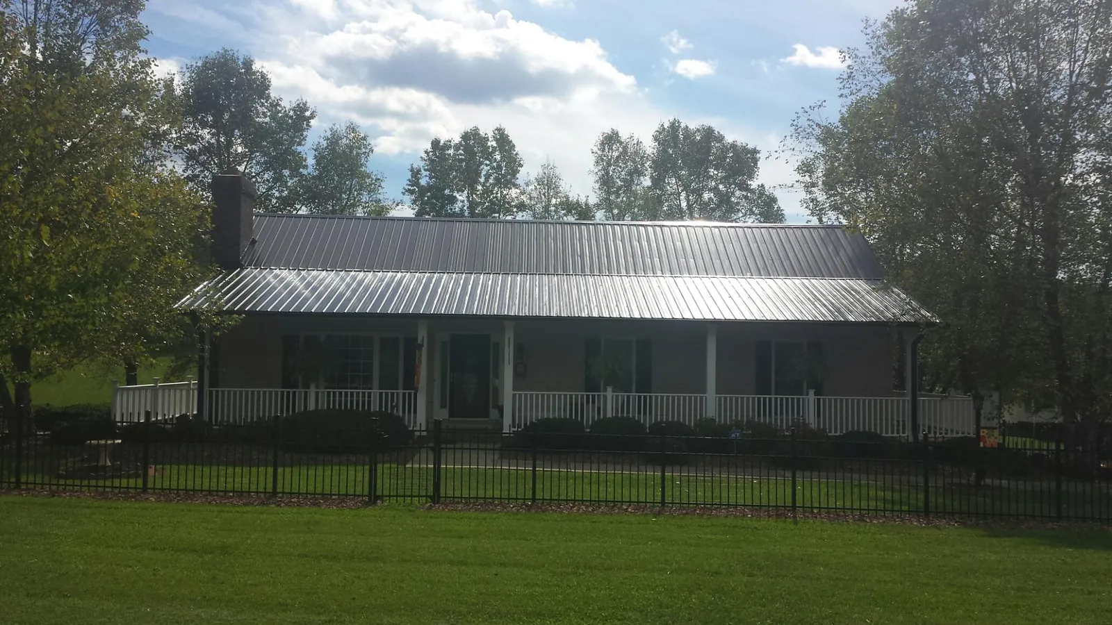 Gray metal roof on a brick ranch with a full width front porch — Gutter Guard Installation work by our crew in Milmay