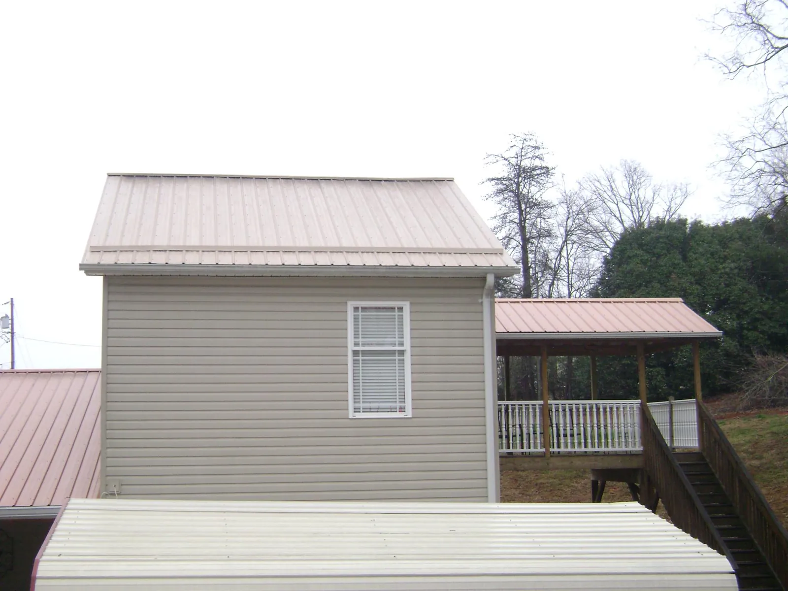 Tan metal roofs on a two story addition and attached porch, from a Roof Replacement job in Milmay