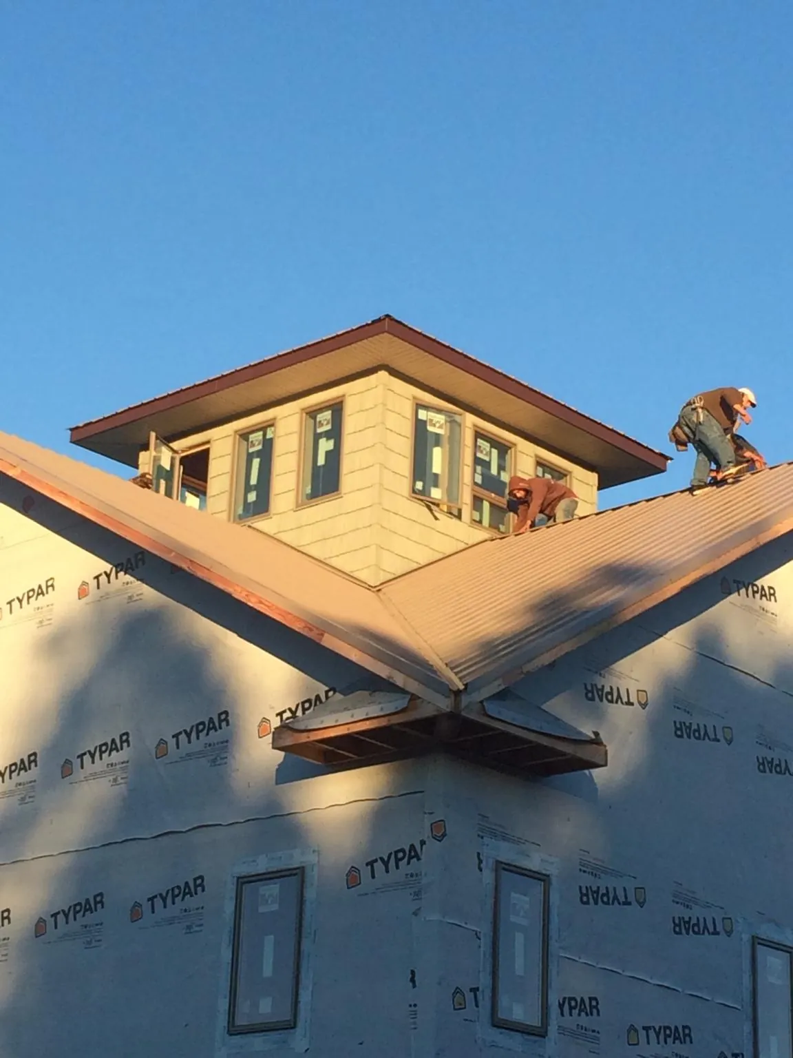 Roofers working around a rooftop cupola on a new metal roof at sunset — Roof Waterproofing in Milmay by Roofing Brothers